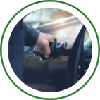A hand grips the door handle of a black car. 